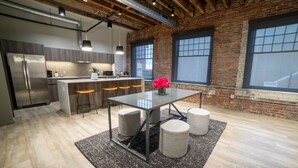 A modern kitchen with a central island, bar stools, and a dining table with stools. - Montvale Hotel (Spokane)