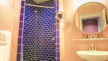 Ein Badezimmer mit einer blauen Duschkabine, einem weißen Waschbecken und einem Spiegel darüber.
