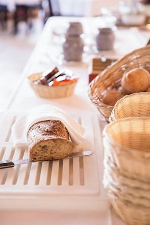 A buffet table with various food items, including bread and pastries, arranged on a white tray.