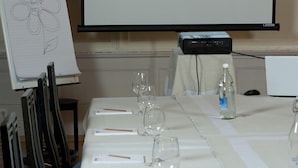A conference table with a projector displaying the Engelberg Hotel Restaurant logo, a whiteboard with a flower sketch, and a water bottle on the table. - Hotel Engelberg das Trail Hotel (Engelberg)