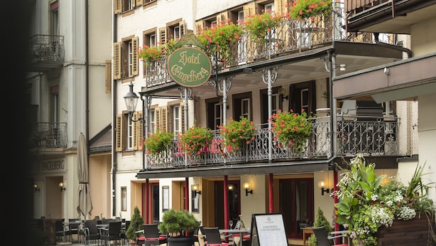 A hotel with outdoor seating, a sign reading "Hotel Engelberg," and balconies with flower boxes. - Hotel Engelberg das Trail Hotel (Engelberg)