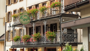 A hotel with a balcony adorned with flowers, outdoor seating, and a signboard. - Hotel Engelberg das Trail Hotel (Engelberg)