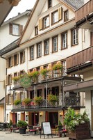 Hotel com varanda decorada com flores, área de estar ao ar livre e placa.
