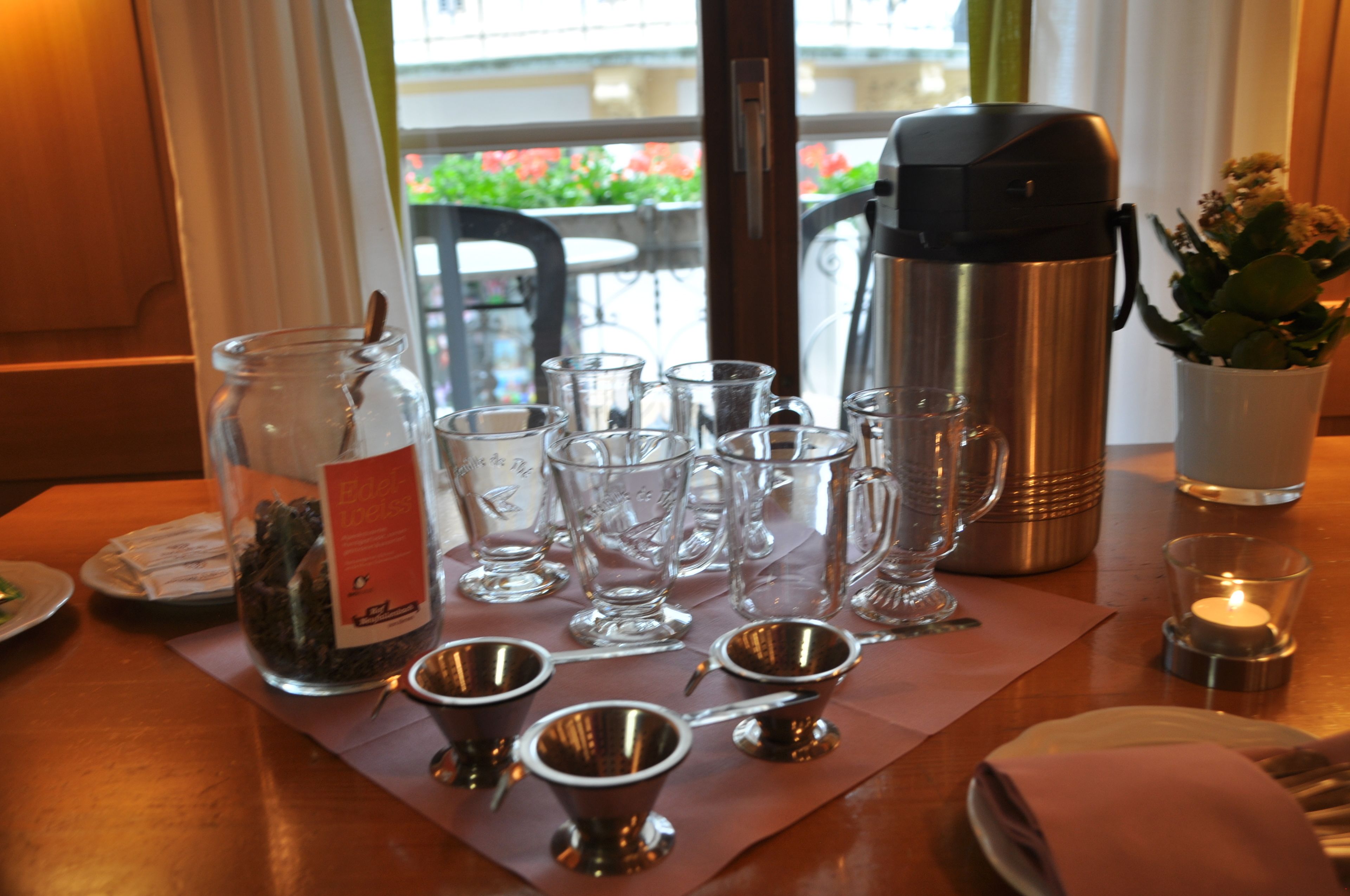 A table set with various glassware, a thermos, and a candle, suggesting a dining or meeting setup.