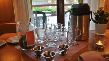 A table set with various glassware, a thermos, and a candle, suggesting a dining or meeting setup.
