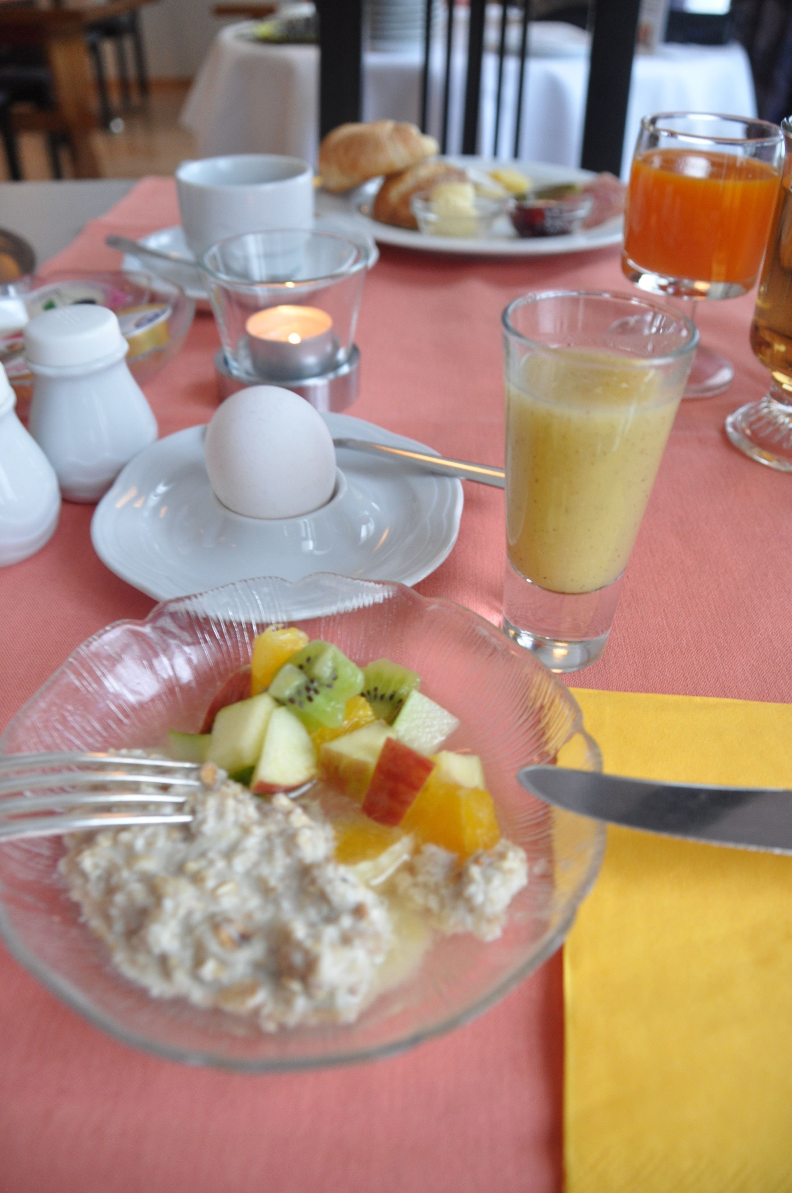 A breakfast setting with a plate of cereal, fruit, and a glass of orange juice.