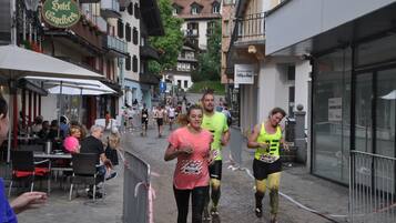 A street with buildings, a hotel sign, and people running.
