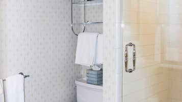 A bathroom with a toilet, a glass shower enclosure, and a towel rack.