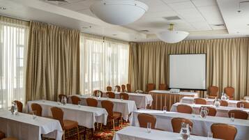 A conference room with multiple tables, chairs, and a projector screen.