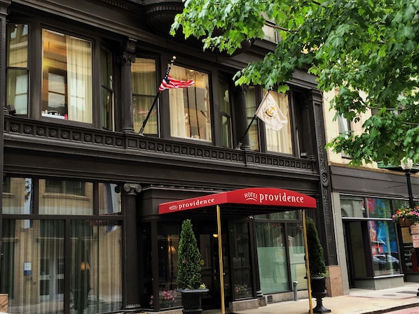 A hotel with a red awning labeled "Hotel Providence," large windows, and a flag.