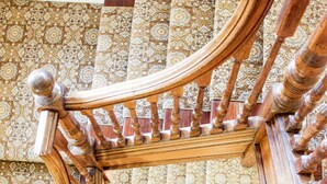Un escalier en colimaçon en bois, doté de rampes décoratives et de carreaux muraux à motifs.