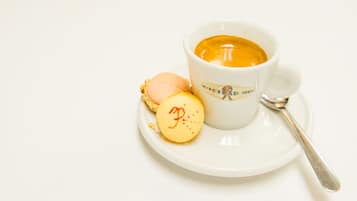 Una taza blanca con cuchara y un plato que contiene un pastelito y una galleta.