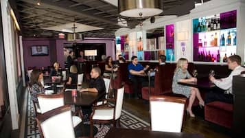 Un restaurant avec des tables et des chaises, un bar avec des bouteilles et un écran de télévision.