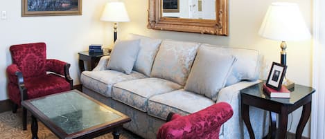 A living room with a sofa, two armchairs, a coffee table, and two lamps.