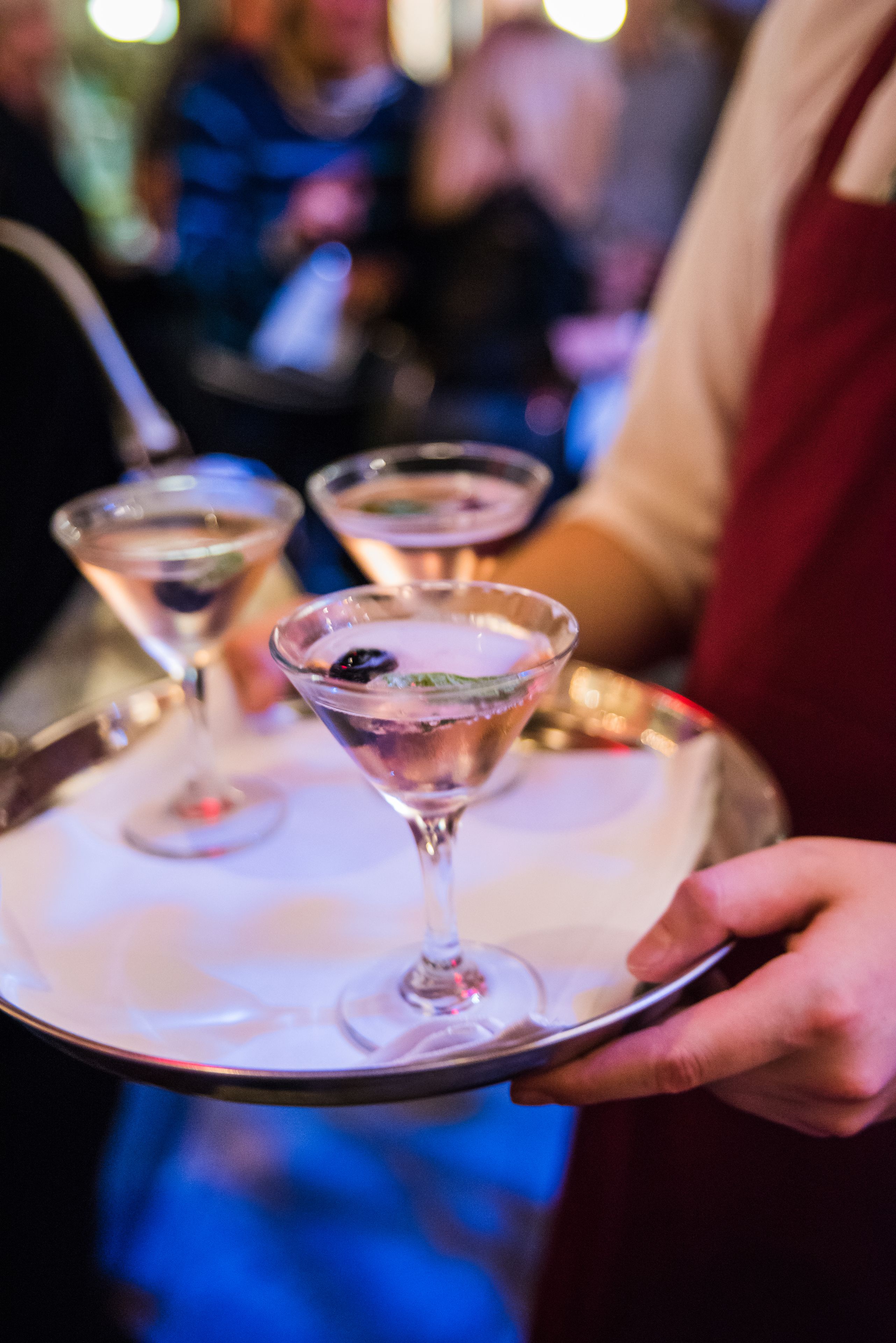 A tray with two martini glasses being held by a person.