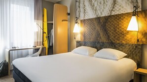 Una camera d'albergo con un letto grande, una scrivania e un armadio.