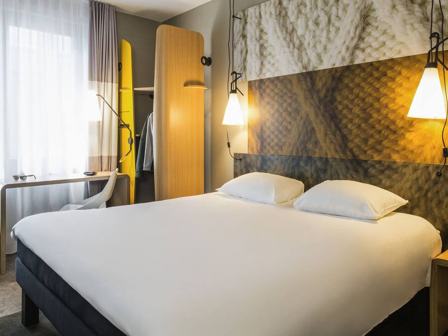 Een hotelkamer met een groot bed, een bureau en een kledingkast.