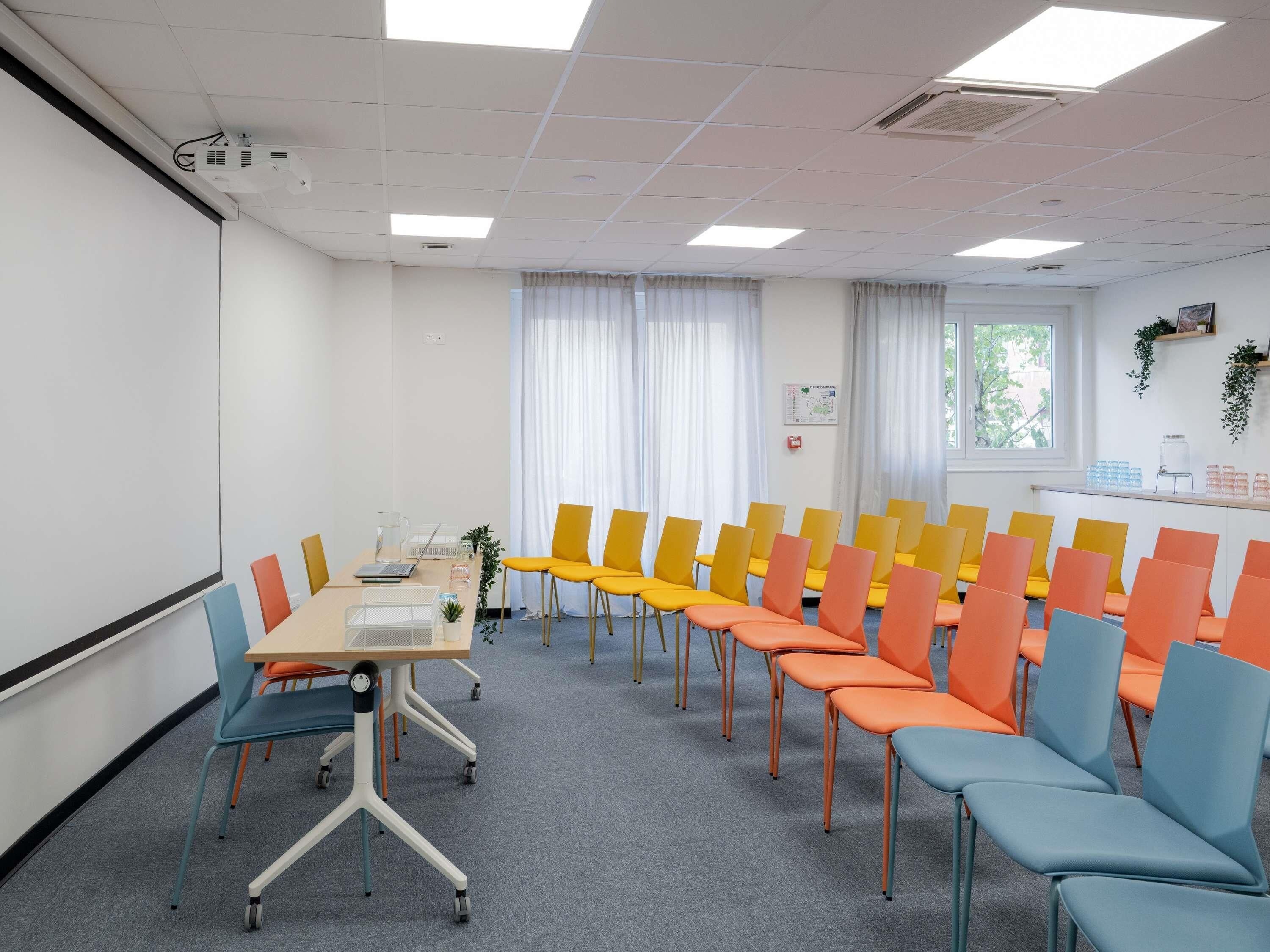 A conference room with a whiteboard, a projector, and a table with chairs.