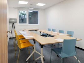 Un salón de conferencias con una larga mesa, sillas y un proyector.