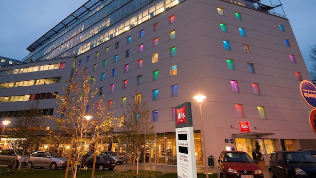 A hotel with a modern glass facade, multiple floors, and a rooftop terrace. - ibis Lyon Caluire Cité Internationale (Caluire-et-Cuire)