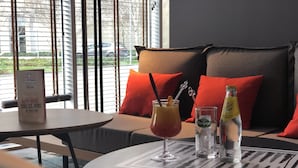 Un'accogliente zona salotto con un tavolo apparecchiato per due, che include una bevanda con un bastoncino per cocktail e una bottiglia d'acqua.