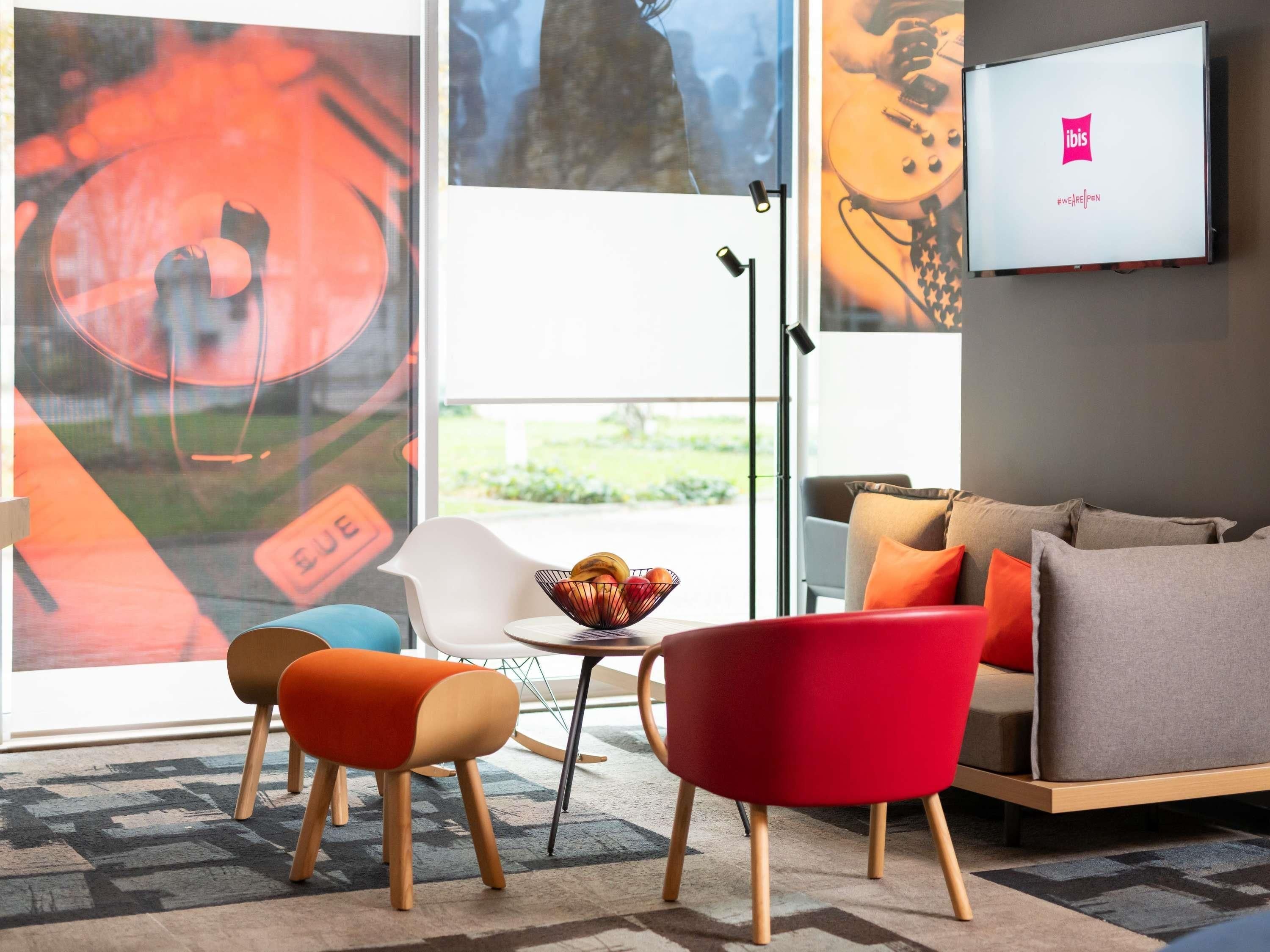 Un salon moderne avec un canapé, des fauteuils, une table basse et un téléviseur fixé au mur.