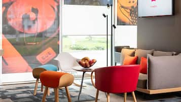 Un salon moderne avec un canapé, des fauteuils, une table basse et un téléviseur fixé au mur.