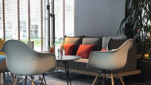 A modern interior with a sofa, two chairs, a table, and a potted plant. - ibis Lyon Caluire Cité Internationale (Caluire-et-Cuire)