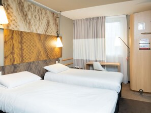 A hotel room with two beds, a desk, a chair, a lamp, and a curtain. - ibis Lyon Caluire Cité Internationale (Caluire-et-Cuire)