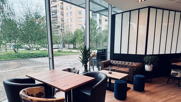 A modern interior with a wooden table and chairs, a leather sofa, and a potted plant. - ibis Lyon Caluire Cité Internationale (Caluire-et-Cuire)