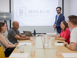 A meeting room with a projector screen displaying 'HOGECO SALLES DE SEMINAIRE'. - ibis Lyon Caluire Cité Internationale (Caluire-et-Cuire)