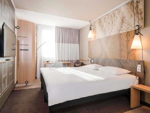 A hotel room with a bed, desk, and wardrobe. - ibis Lyon Caluire Cité Internationale (Caluire-et-Cuire)