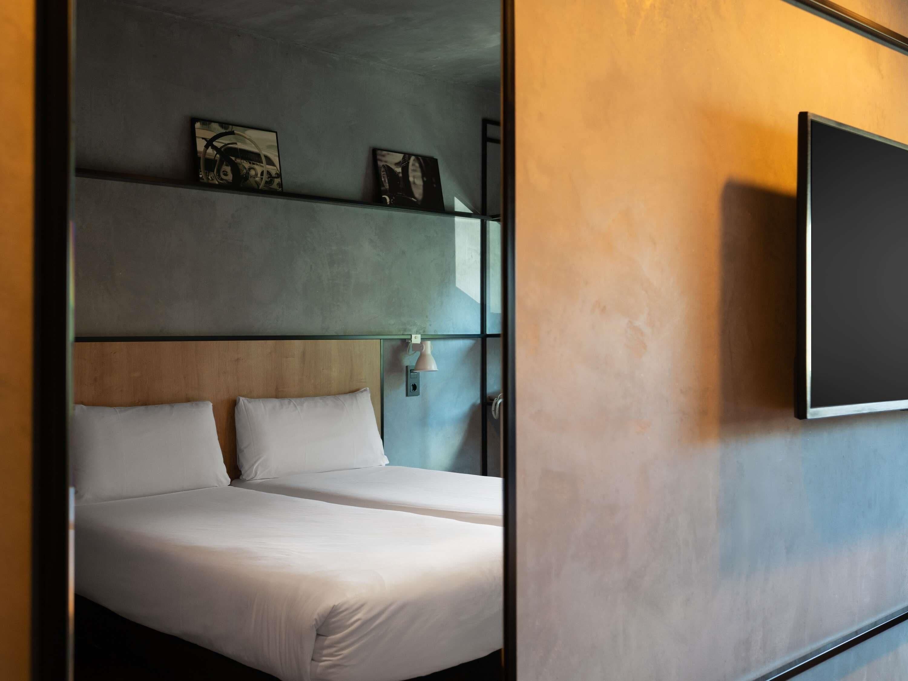 Una habitación de hotel con una cama, televisor y obras de arte en la pared.