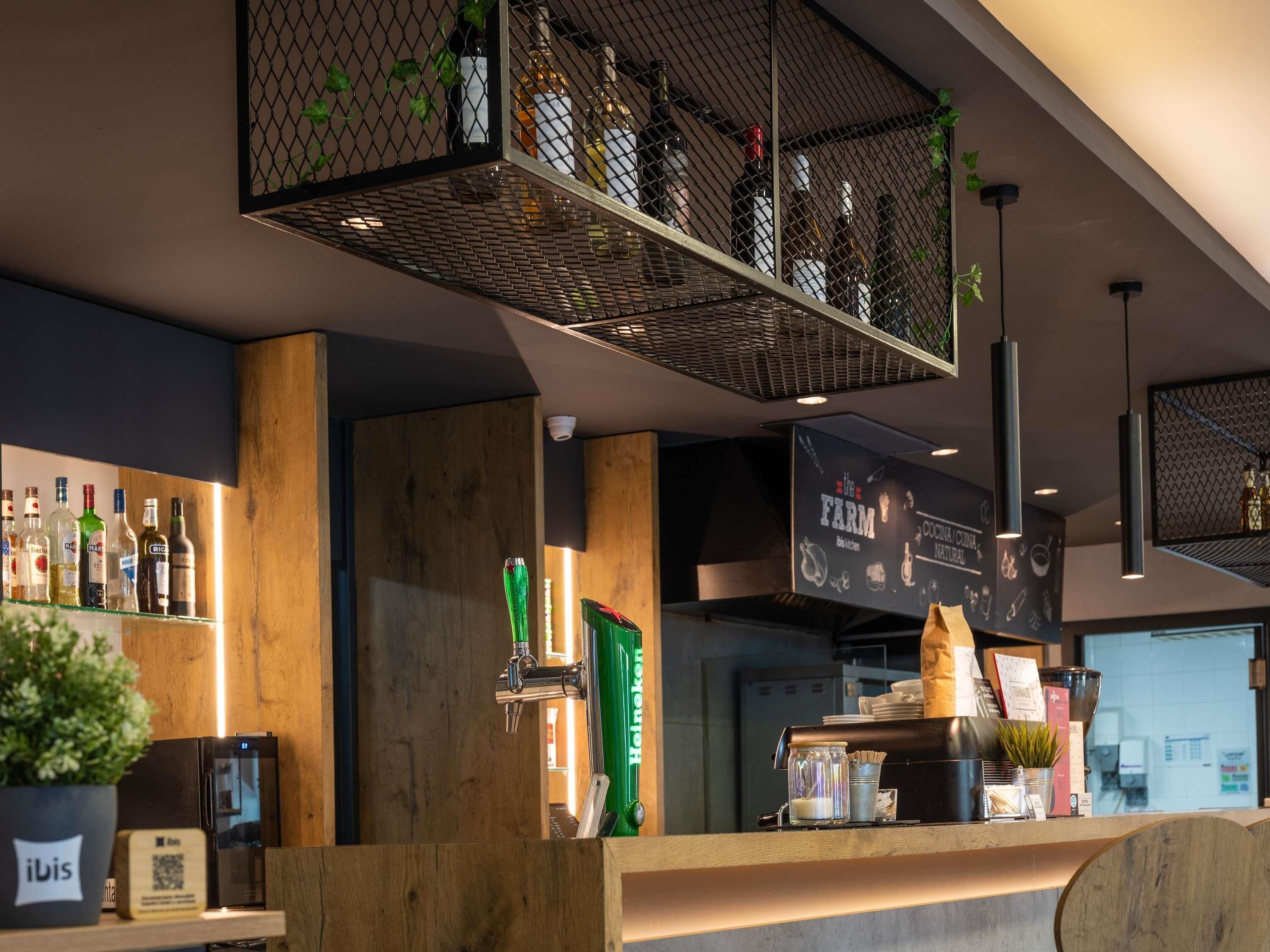 A bar area with a counter, shelves with bottles, a coffee machine, and a menu board.