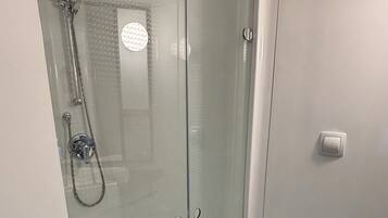 Un baño moderno con ducha envuelta en vidrio, inodoro y lavamanos.