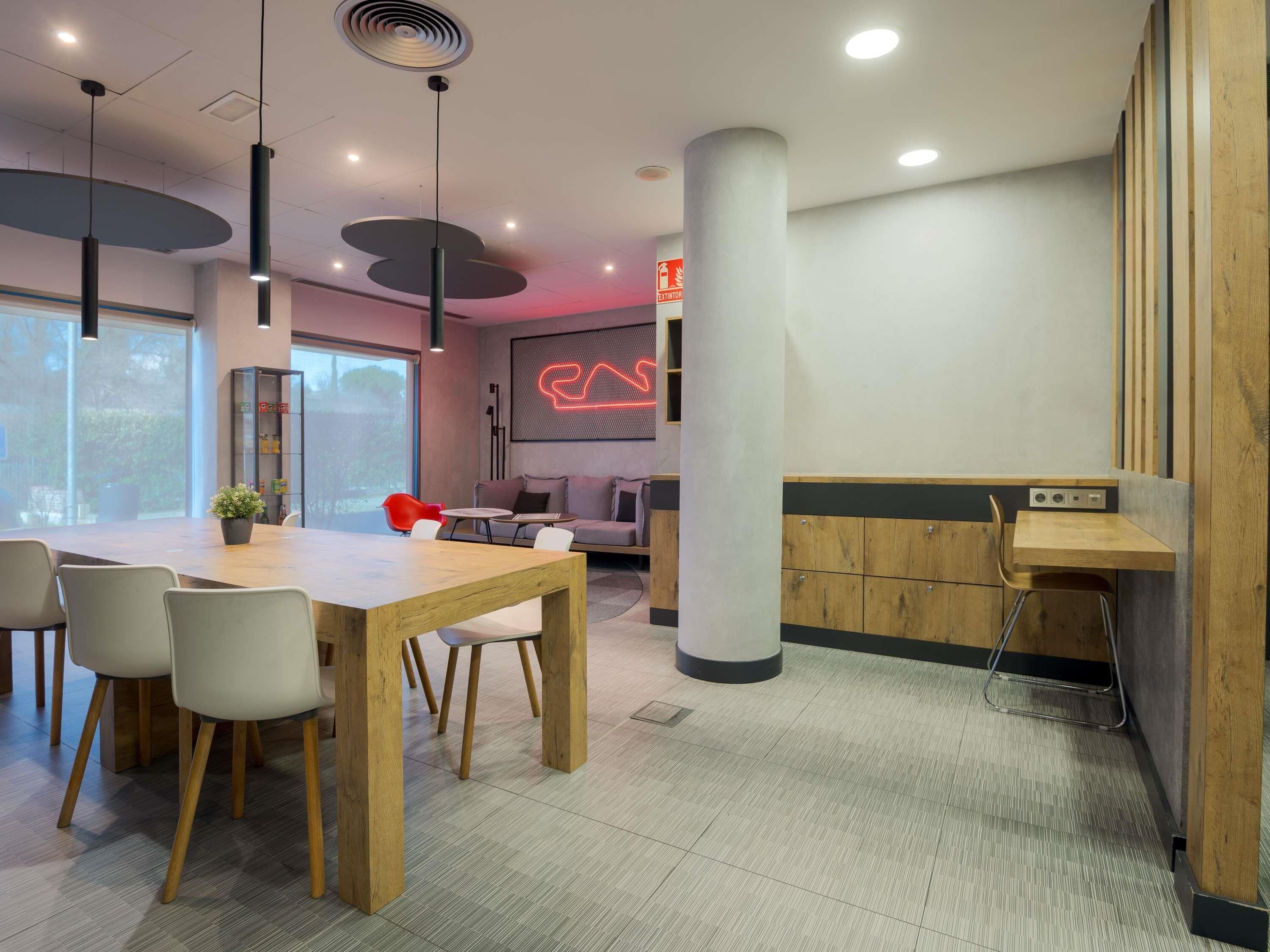 Un interior moderno con una mesa de madera para comer, sillas, un sofá y un letrero de neón.
