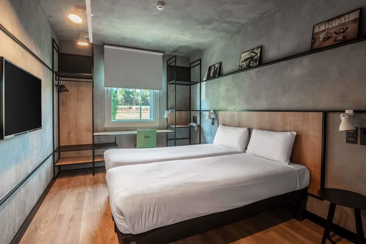 A modern bedroom with a large bed, a desk, and a window.