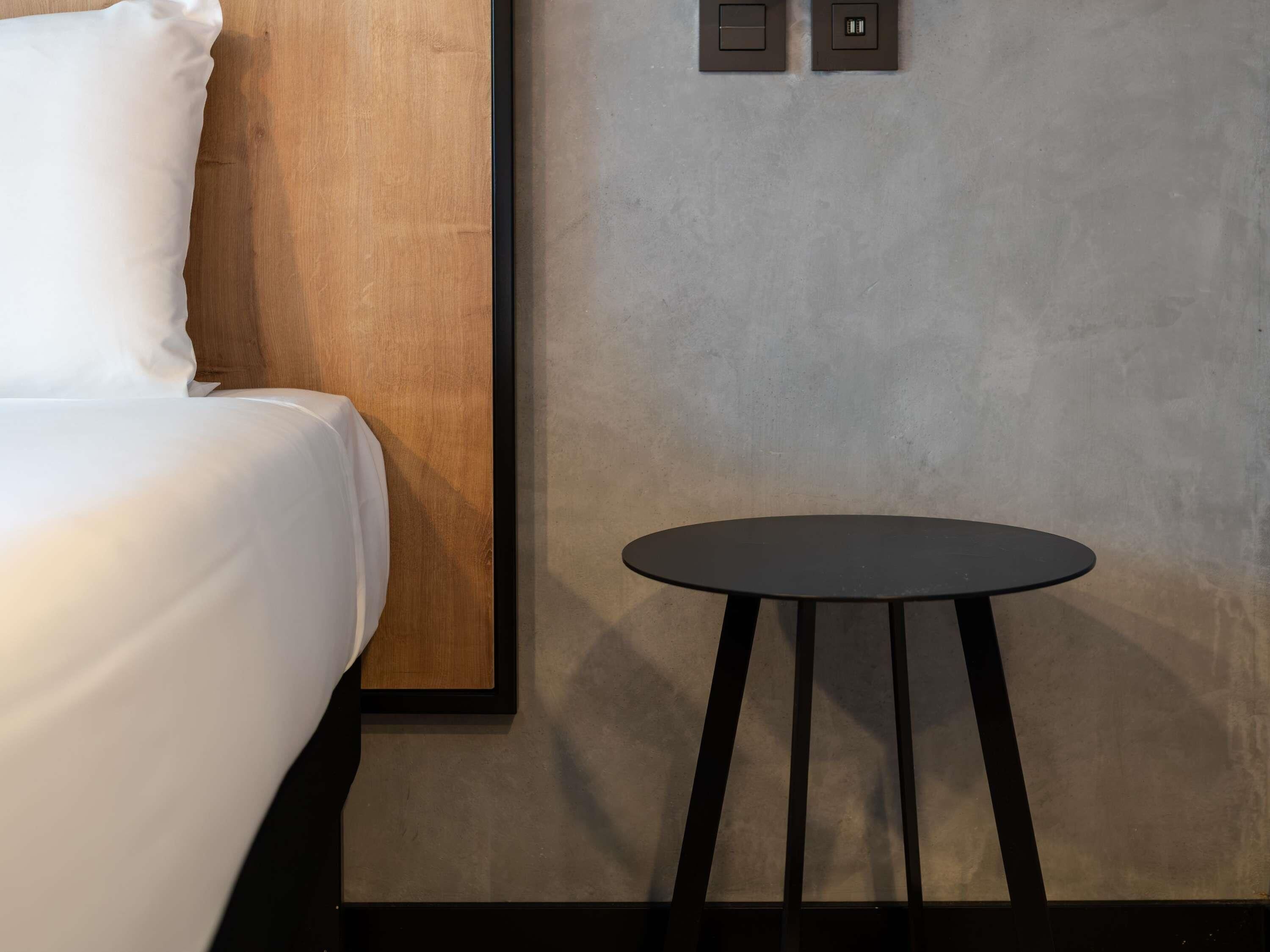 Una habitación de hotel con cama, una mesita redonda y un panel de madera en la pared.