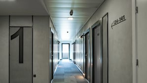 A long, narrow hallway with a checkered carpet, doors on the right, and a number sign on the left. - ibis Barcelona Montmelo-Granollers (Granollers)