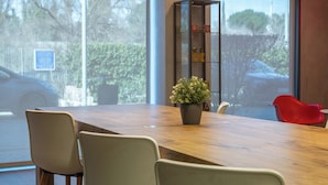 A modern dining area with a wooden table, four chairs, a potted plant, and pendant lighting. - ibis Barcelona Montmelo-Granollers (Granollers)