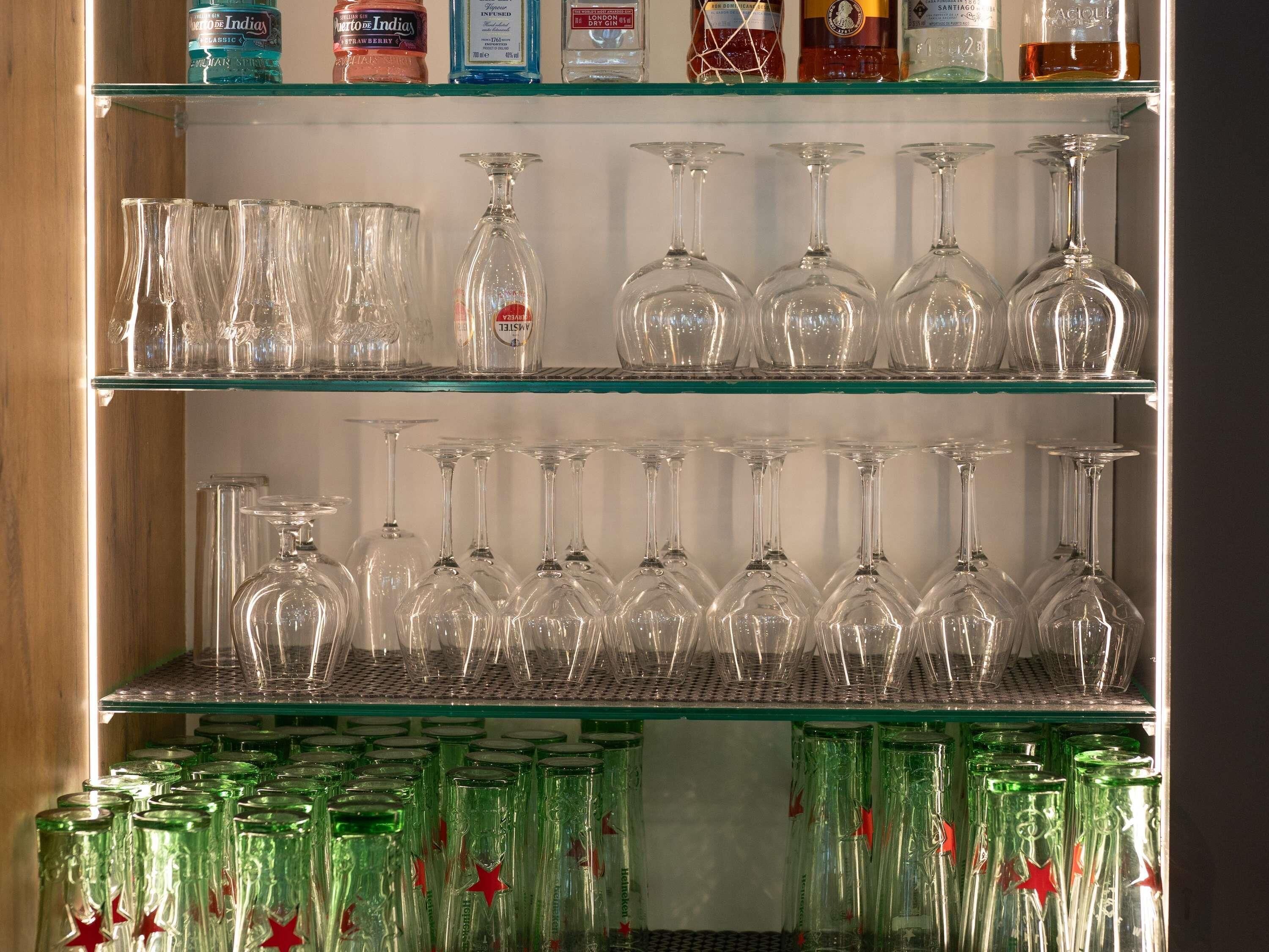 Una estantería con diferentes vasos y botellas, incluyendo copas de vino y licores.