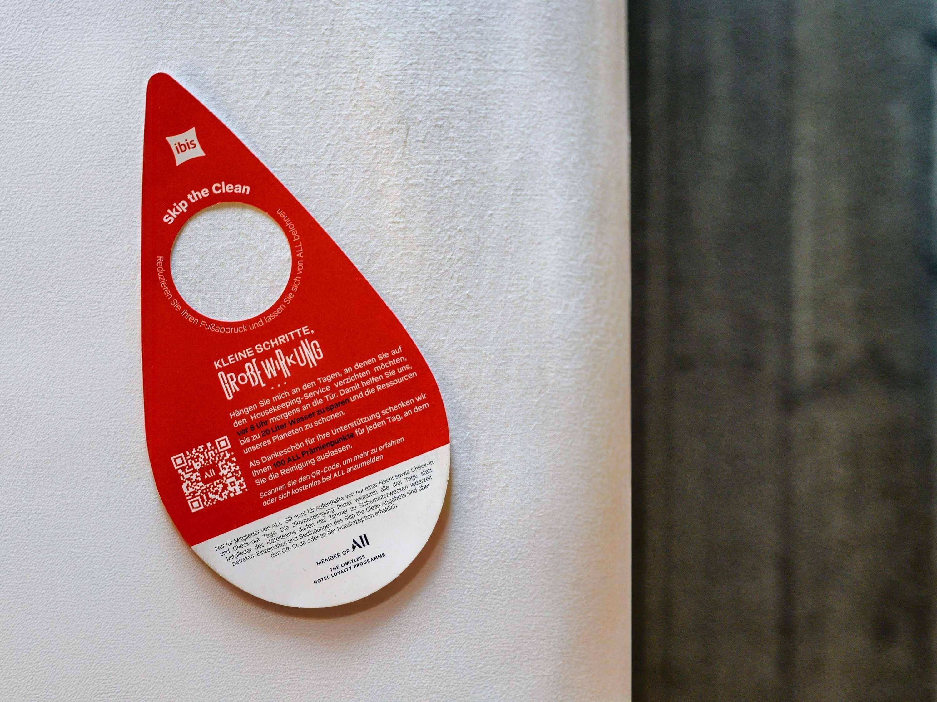 A red tag with white text and a QR code on a white wall.