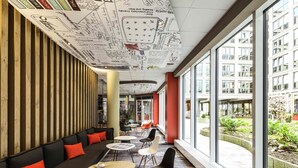 Un intérieur moderne avec un long espace salon, des tables et de grandes fenêtres offrant une vue sur l’extérieur.