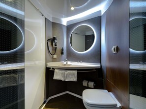 Een moderne badkamer met een ronde spiegel, een wit wastafelmeubel en toilet.