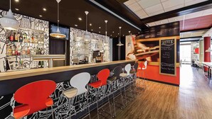 Un espace bar moderne doté d’un long comptoir, de nombreux tabourets et d’un tableau affichant le menu.