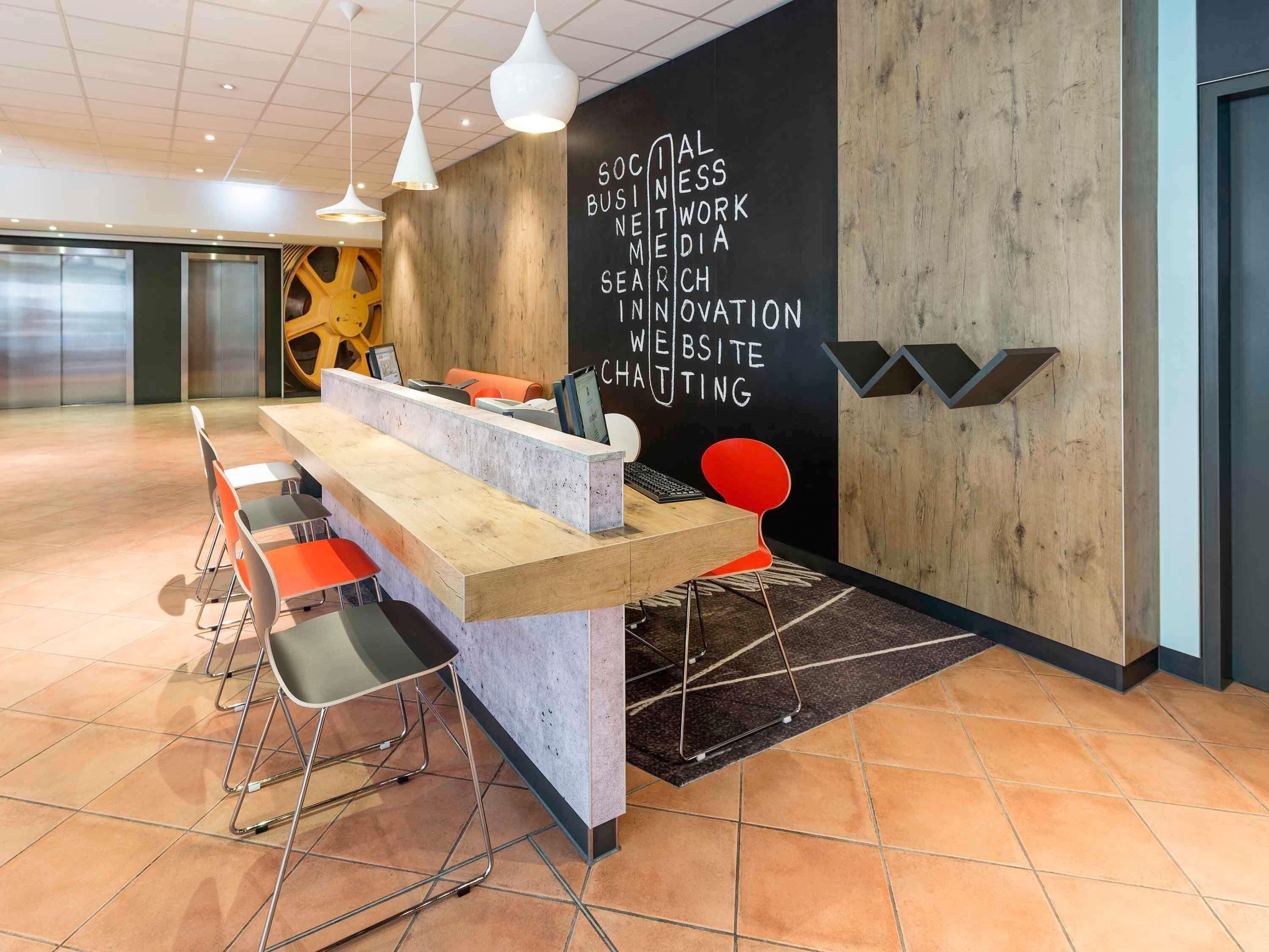 Un área de recepción con mostrador, sillas y una pared con texto.