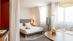 A hotel room with a bed, bedside table, and a small dining table. - Novotel Suites Cannes Centre (Cannes)