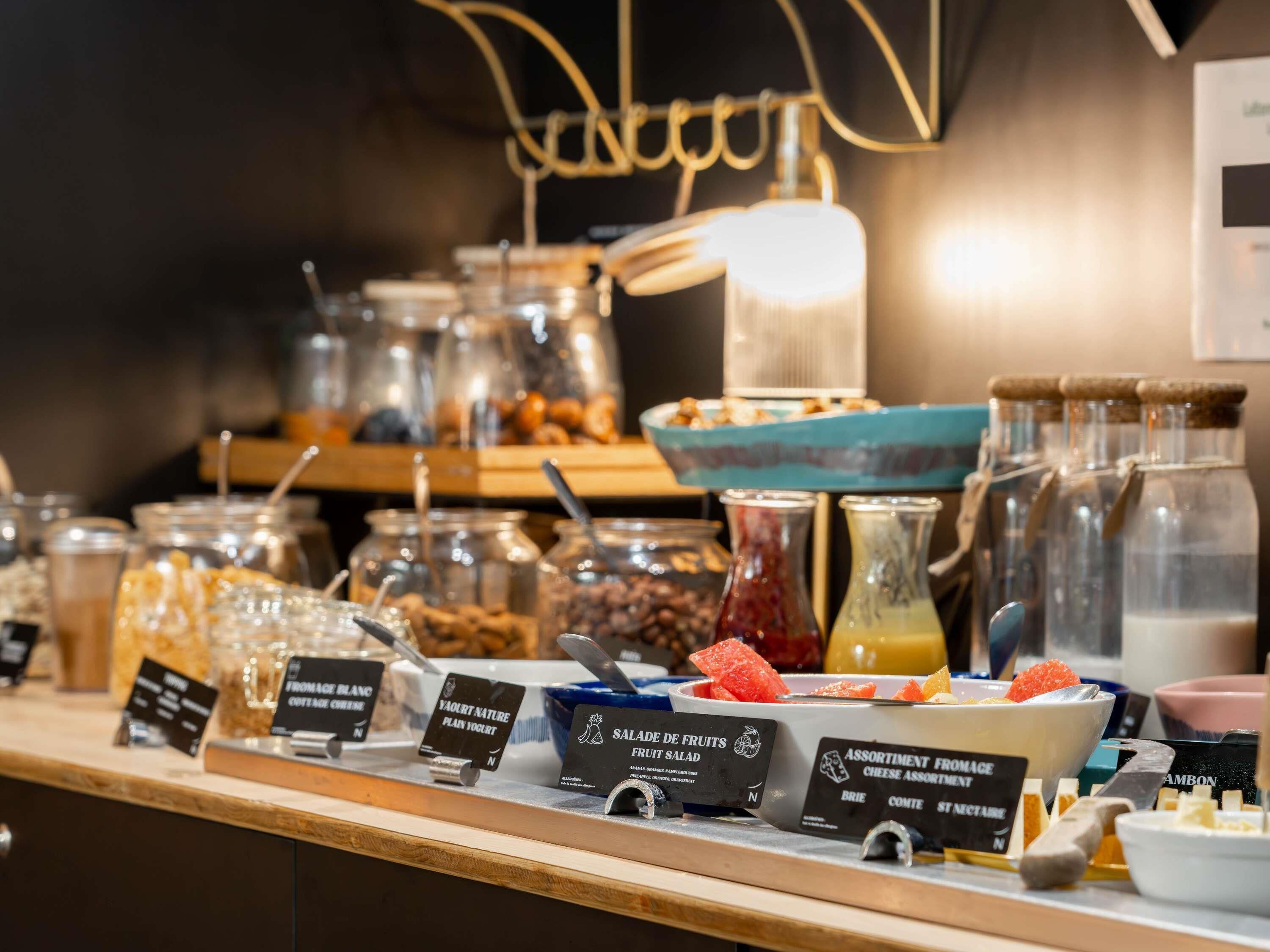 Ein reichhaltiges Buffet mit verschiedenen Speisen, darunter Joghurt, Obstsalat und Käsesorten.