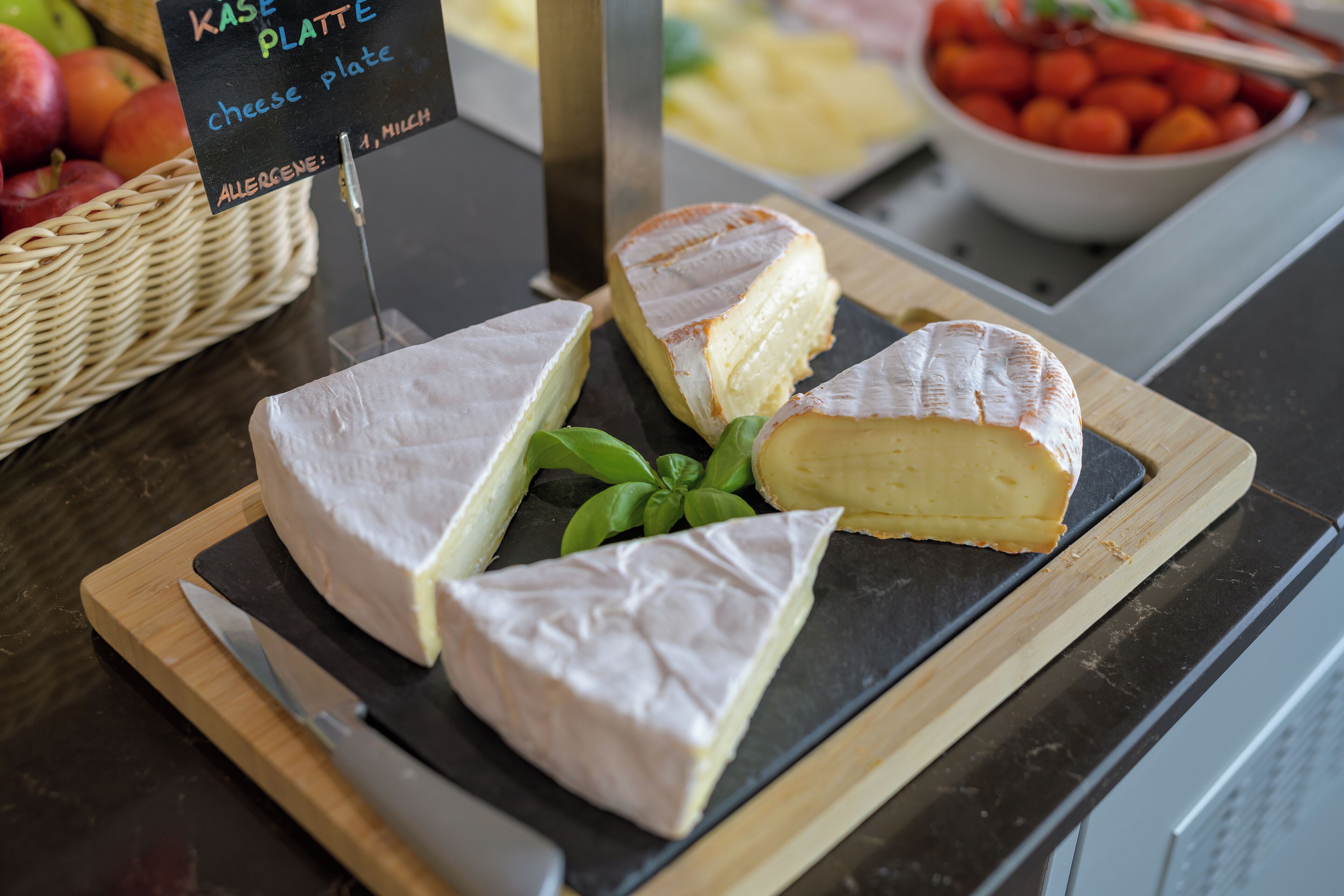 A cheese board with various types of cheese and a sign indicating the cheese plate is allergen-free.