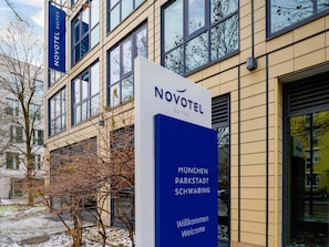 Señal de Novotel Suites con la inscripción 'München Parkstadt Schwabing' y 'Willkommen Welcome'.